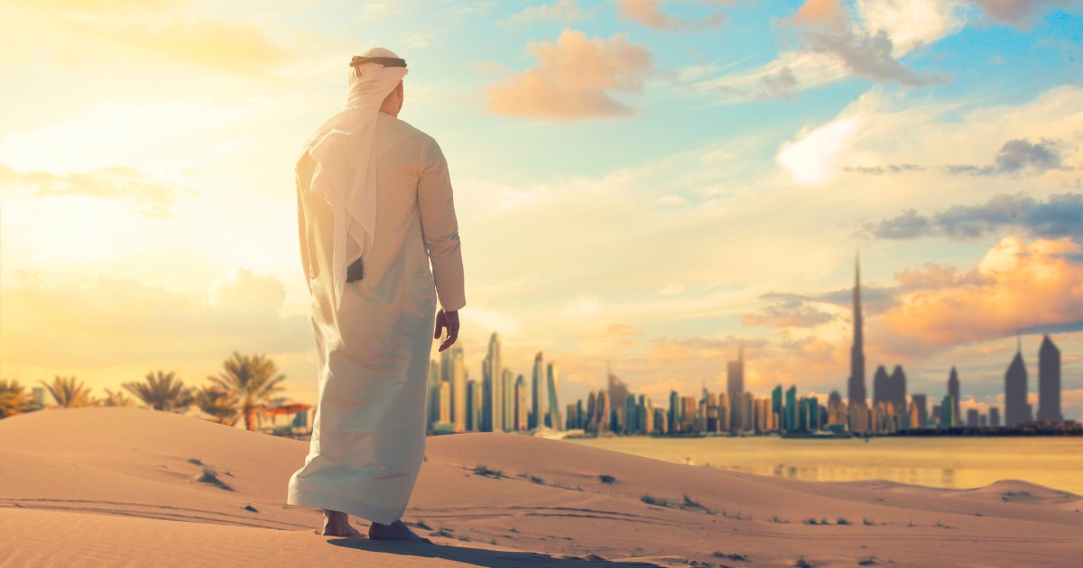 Arab man standing front Dubai skyline in the desert of UAE