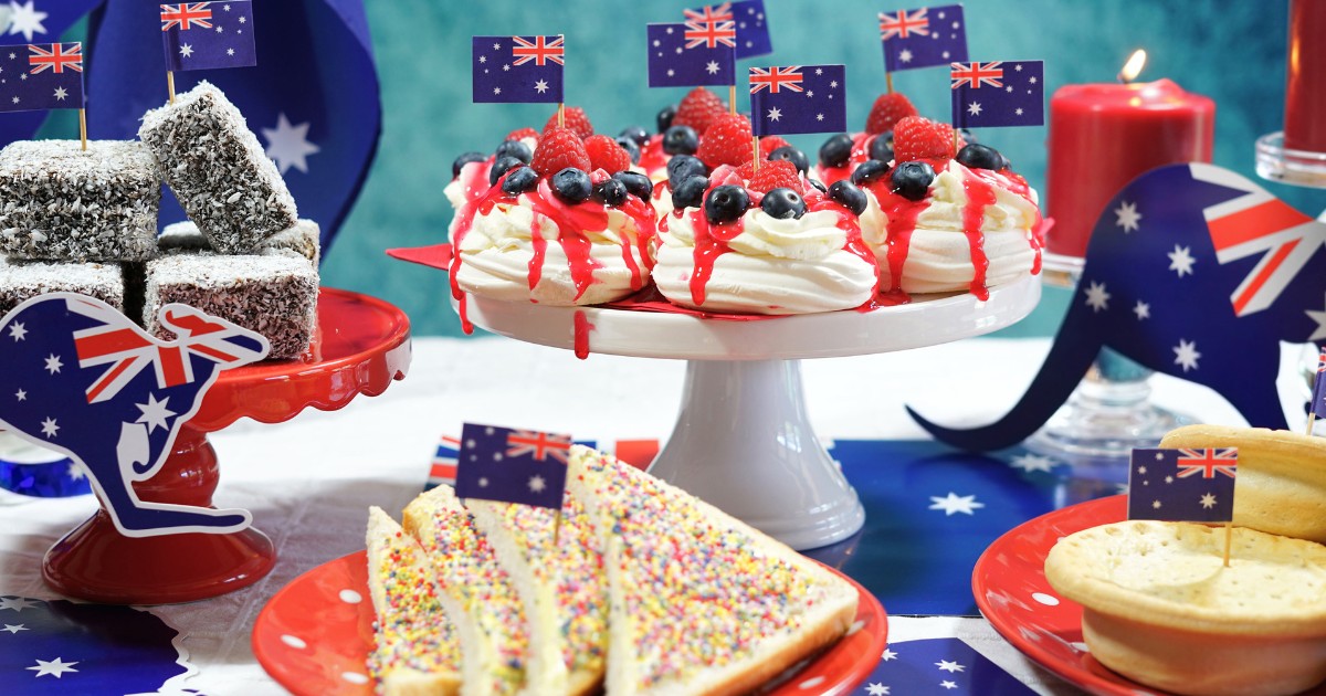 Australian theme party table with flags and iconic food including mini pavlovas, lamingtons, meat pies and fairy bread.