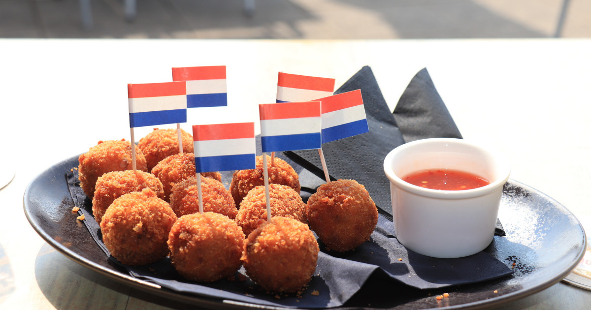 Dutch Bitterballen with mustard, warm stuffed fried meatballs, served in the Netherlands and decorated with the dutch flag