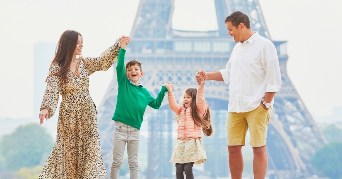 Happy family of four enjoying their trip to Paris, France. Mother, father, son and daughter near the Eiffel tower in Paris. Married couple with kids travelling in France
