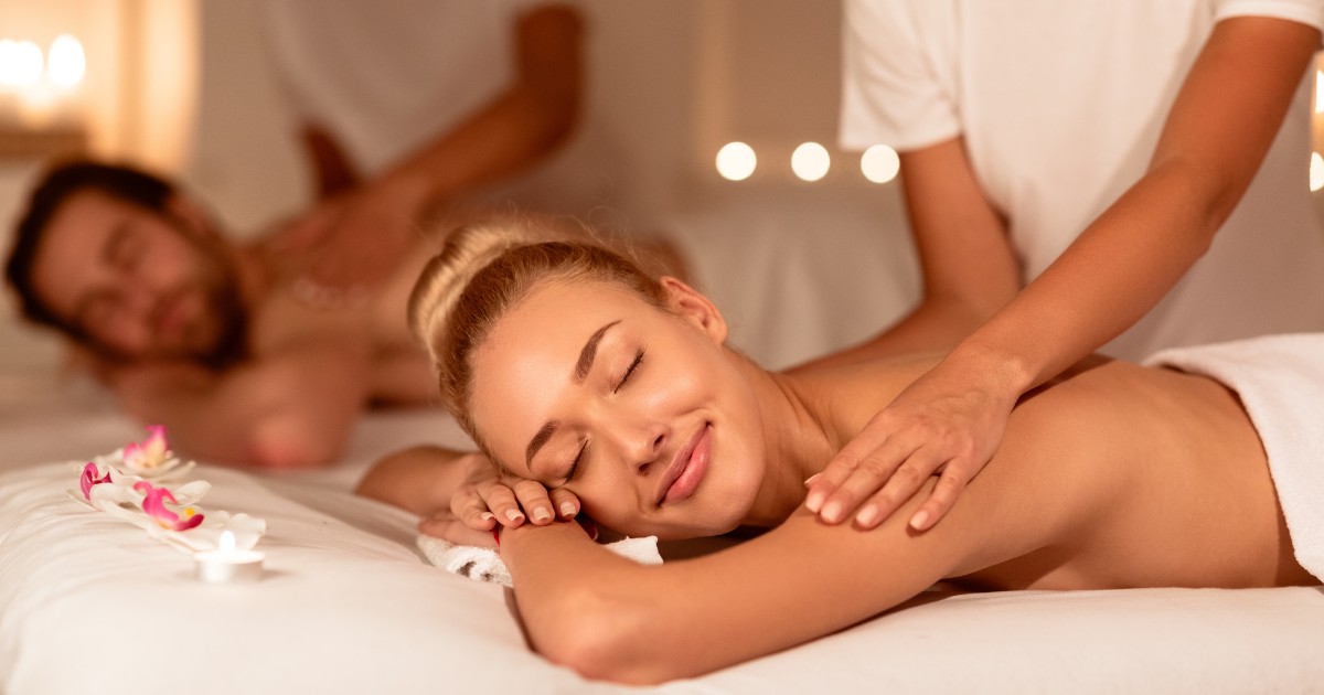 Spouses-Relaxing-During-Massage-And-Aromatherapy-Lying-Together-On-Beds-At-Luxury-Spa-Resort