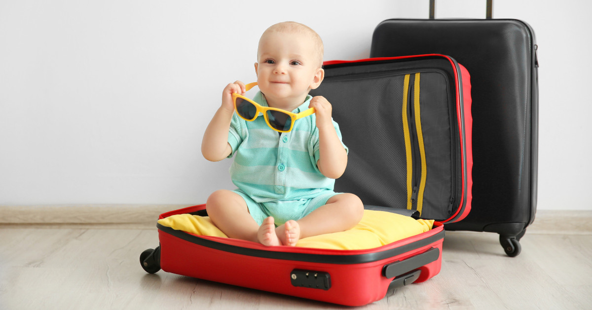 Toddler sat in a suitcase holding yellow sunglasses