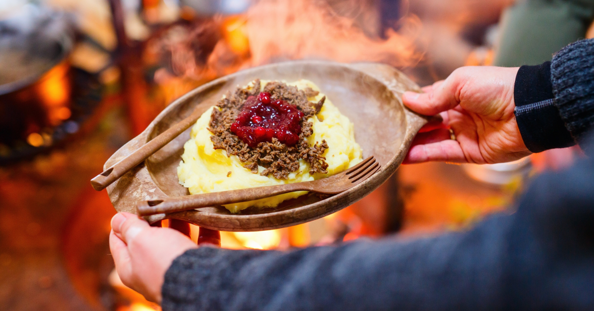 Traditional finnish food sauteed reindeer with mashed potatoes and lingonberries served in lappish hut next to open fire