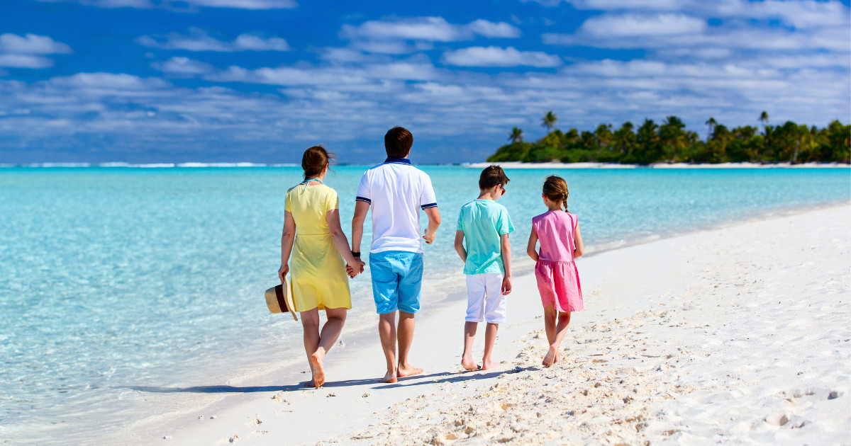 Family of four walking along sandy beach